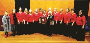 The Carlson Chorale pictured after the Ryde Eisteddfod win. L-R Adjudicator Pamela Herring, Ryde Eisteddfod Chairman Edna Wilde OAM, Sarah Woolley, Kathryn Jenkins, Lesley Wilson, Marilyn Murray, Jenny Holmes, Carole Handley, Beth Treseder, Rosalind Carlson (with shield), Julie Watts, Corinne Lodewijks, Rhys Kitto, Rosanne Jackson, Elizabeth Willis.