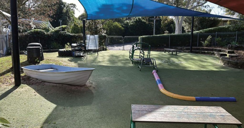Outdoor playground with a boat, shade sail, and sports equipment in Galston community park.