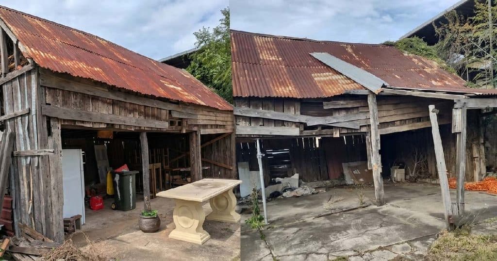 Old wooden shed with rusted metal roof in rural area.