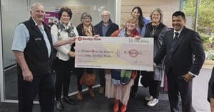 Group of people holding a large check at Bendigo Bank event.
