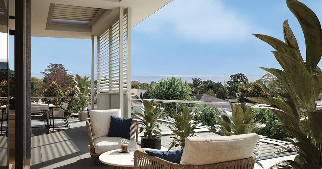 Balcony with outdoor seating overlooking lush greenery and distant hills.