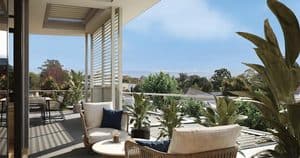 Balcony with outdoor seating overlooking lush greenery and distant hills.
