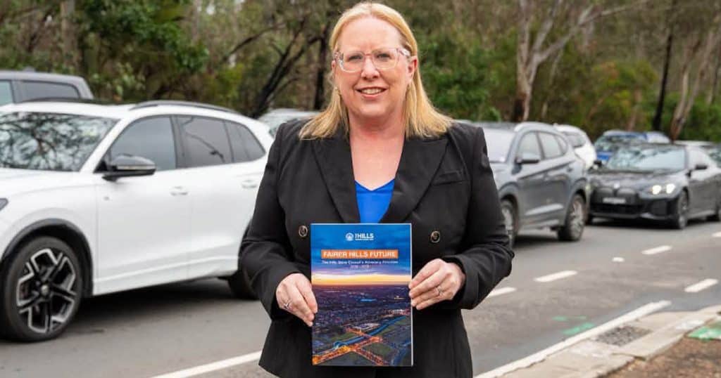 Woman holding a report titled 'Fairer Future' outdoors with parked cars behind.
